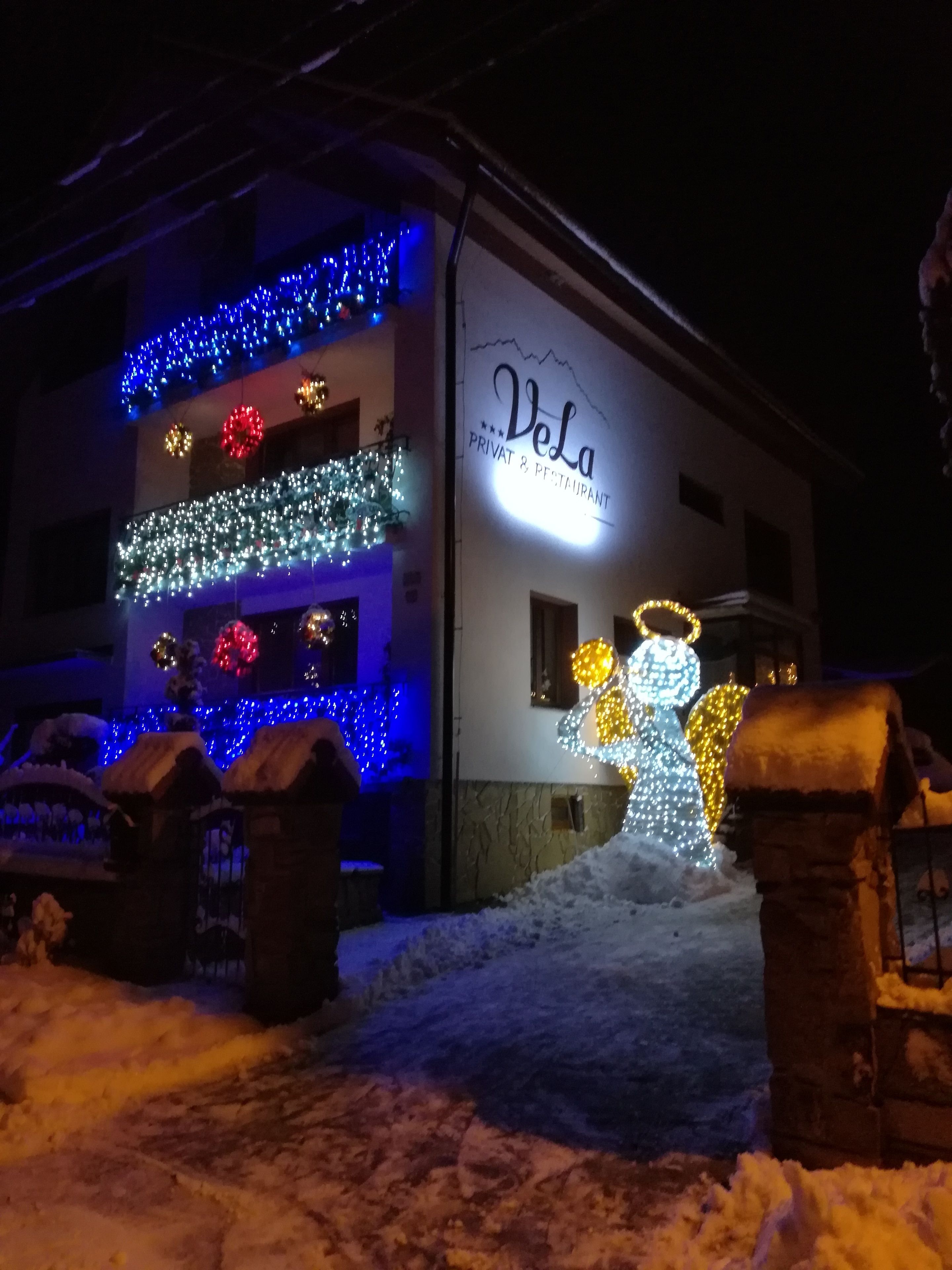 A building with a sign reading "Vela Privat & Restaurant" and decorative lights.