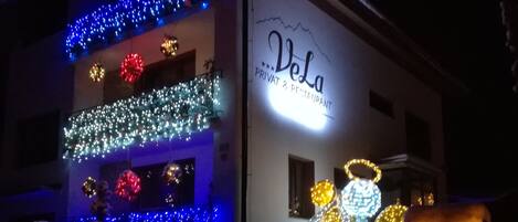 A building with a sign reading "Vela Privat & Restaurant" and decorative lights.