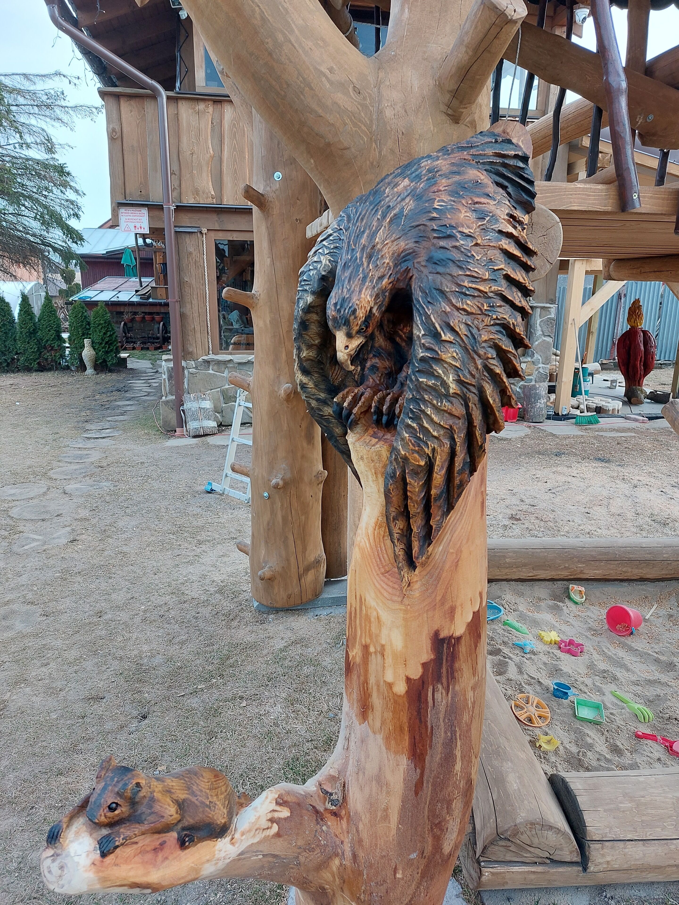 Eine hölzerne Skulptur eines Adlers, der auf einem Ast sitzt.