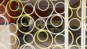 A room with a patterned glass door and a view of a dining area with chairs and tables. - Pinnacle Court Apartments (Nairobi)