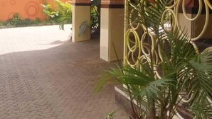 A hotel entrance with a tiled walkway, a potted plant, and a decorative wall. - Pinnacle Court Apartments (Nairobi)