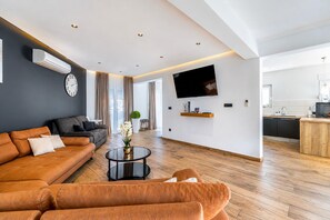 A modern living room with a sofa, coffee table, and a flat-screen TV mounted on the wall.