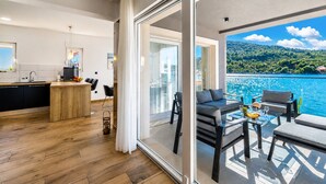 A modern kitchen with a wooden island, a dining area with a table and chairs, and a balcony with a view of the sea. - Beachront Luxury Villa w/rooftop pool, gym + spa Only 20 Min. From Split Airport (Vinišce)