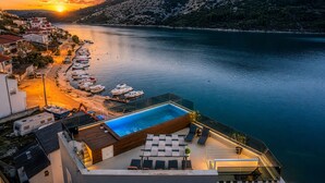 A rooftop pool with lounge chairs, a view of the sea, and boats docked along the shore. - Beachront Luxury Villa w/rooftop pool, gym + spa Only 20 Min. From Split Airport (Vinišce)