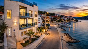 A coastal hotel with a modern design, featuring balconies, a paved walkway, and a marina in the background. - Beachront Luxury Villa w/rooftop pool, gym + spa Only 20 Min. From Split Airport (Vinišce)