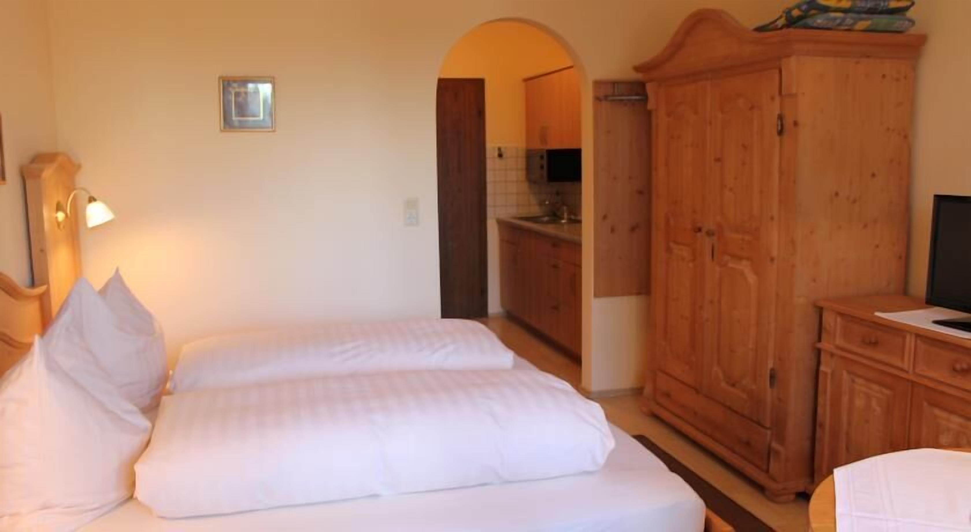 Une chambre à coucher avec un lit, une armoire en bois et un téléviseur.