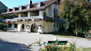 A building with a balcony, arched doorways, and a courtyard. - Apparthotel Jagdhof (Bad Griesbach im Rottal)