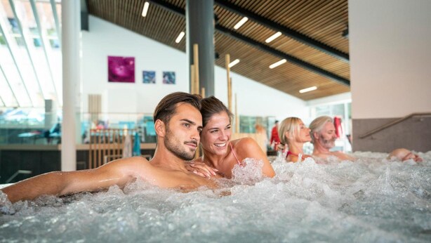 A couple in a hot tub with other people in the background. - Apparthotel Jagdhof (Bad Griesbach im Rottal)