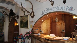 A reception area with a wooden reception desk, antler decorations, and a sign reading "Reception". - Apparthotel Jagdhof (Bad Griesbach im Rottal)