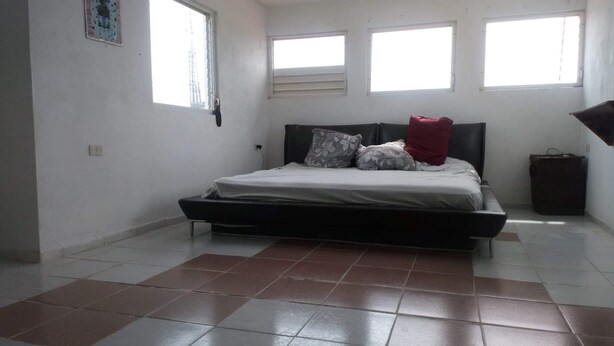 Un dormitorio con una cama, una ventana y un cubo de basura.