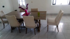Un comedor con una mesa de madera, cuatro sillas y un florero con flores.