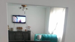 Una sala de estar con un sofá, un televisor y una mesa de comedor.