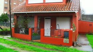 Una casa roja con techo de tejas, puerta principal y un pequeño porche.