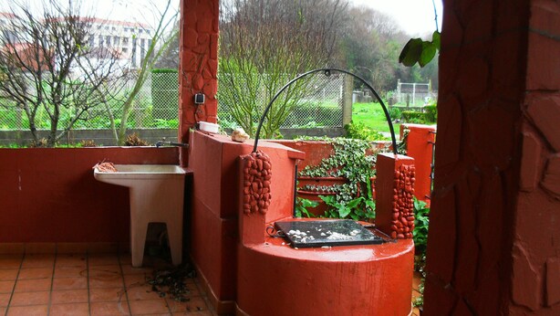 Un espacio exterior techado con una estructura de ladrillo rojo, un lavabo y una parrilla.