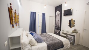 Een slaapkamer met een bed, een bureau, een televisie en een kledingkast.