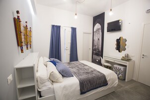 A bedroom with a bed, a desk, a TV, and a wardrobe.