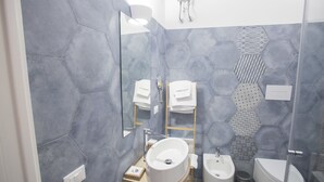 Een moderne badkamer met een grote spiegel, een wastafel, een toilet en een douche.