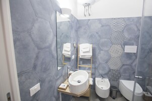 A modern bathroom with a large mirror, a sink, a bidet, and a shower.