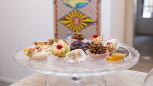 Een glazen taartplateau met diverse gebakjes op een houten tafel.