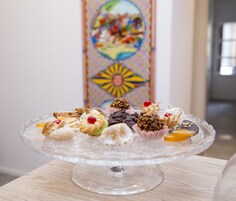 A glass cake stand with assorted pastries on a wooden table.