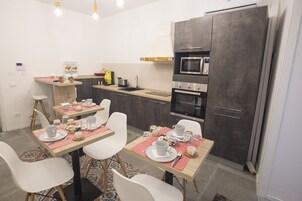 A modern kitchen with a dining area set for four, including a table with chairs, a microwave, and a built-in oven.