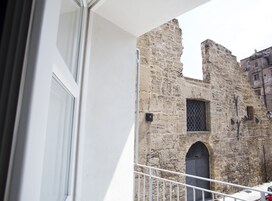 A balcony with a view of a stone building with a window and a door.