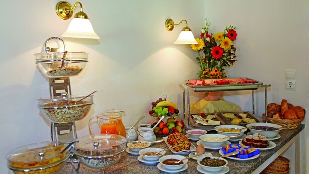 A buffet with various food items and a flower arrangement.