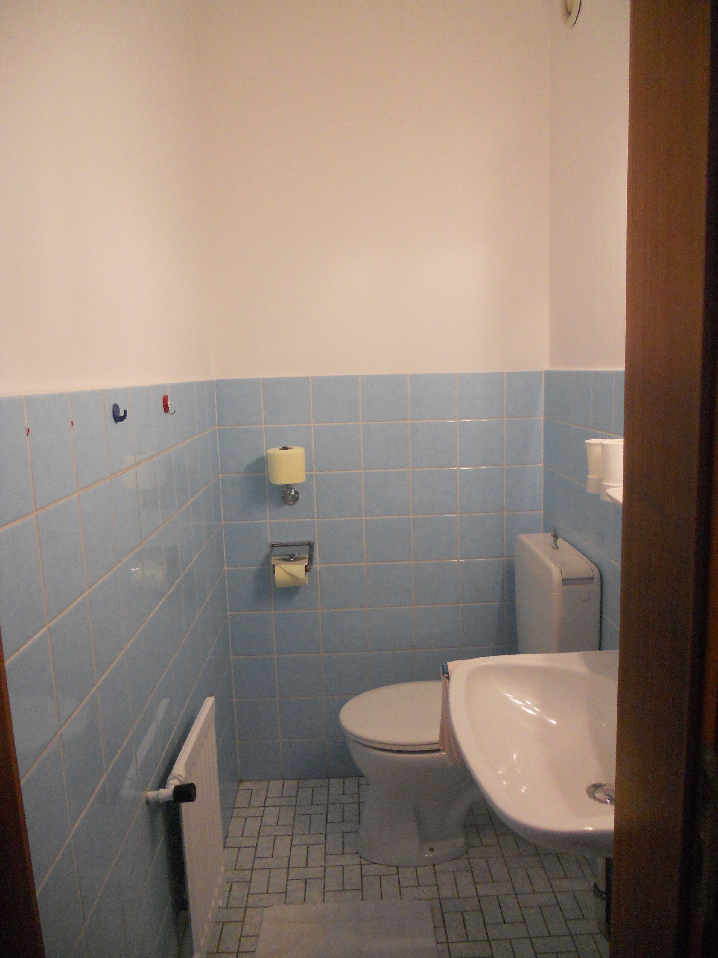 A bathroom with a toilet, sink, and blue-tiled walls.