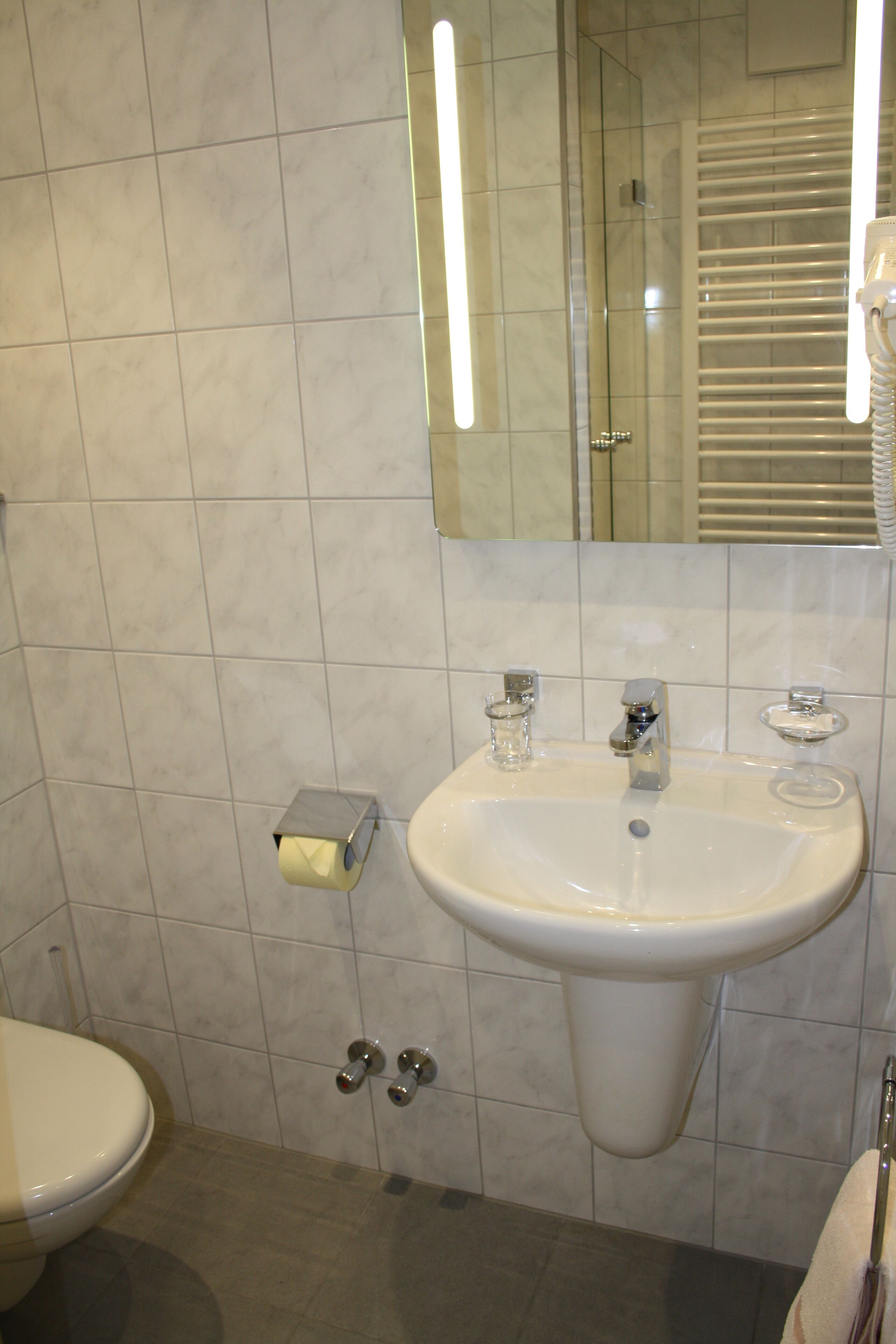 A bathroom with a white sink, a mirror, and a toilet.