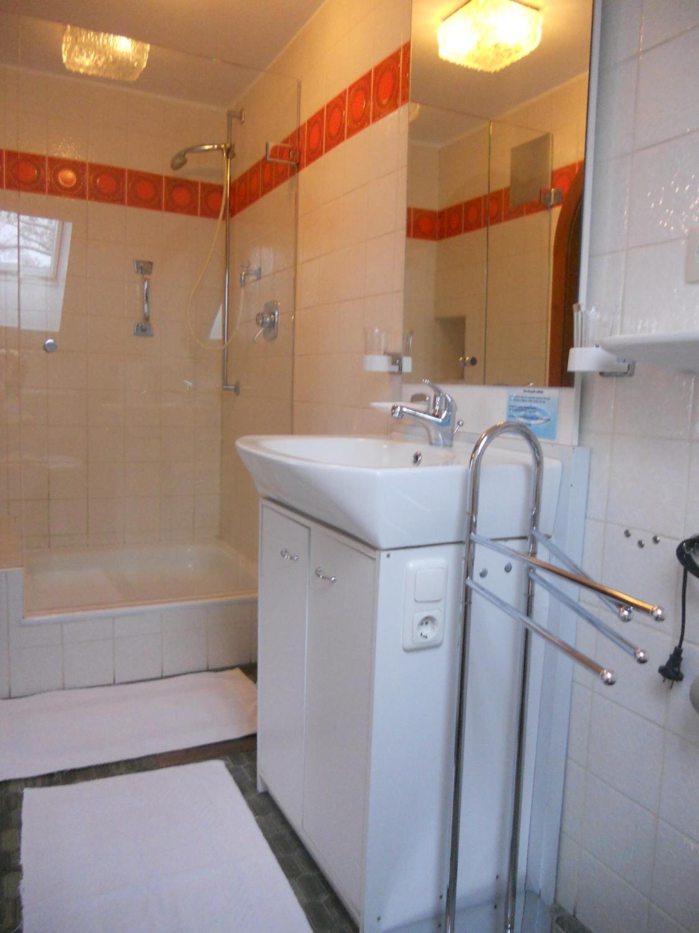 Un baño con lavamanos blanco, un espejo, ducha y bañera.