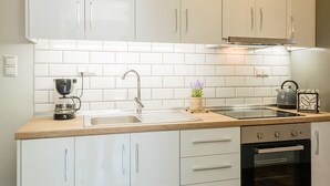 A modern kitchen with white cabinets, a wooden countertop, a coffee maker, and an oven.