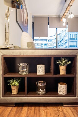 A modern living room with a wooden console table, decorative jars labeled "Home Sweet Home," and a potted rosemary plant. - HOMESWEETHOME (Thessaloniki)