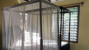 A room with a four-poster bed covered by a sheer canopy, a window with metal bars, and a wooden bench. - Villa with big Pool, 3 minutes to the stunning white beach (Diani Beach)