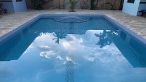 A rectangular swimming pool with a tiled edge and a clear blue water surface reflecting the sky and clouds. - Villa with big Pool, 3 minutes to the stunning white beach (Diani Beach)