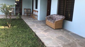 A covered outdoor area with a stone floor, a wicker sofa, and a small tree with white flowers. - Villa with big Pool, 3 minutes to the stunning white beach (Diani Beach)