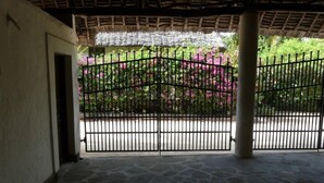 A covered outdoor area with a stone floor, a metal gate, and a thatched roof. - Villa with big Pool, 3 minutes to the stunning white beach (Diani Beach)