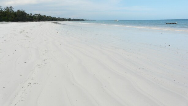 A wide, sandy beach with a calm sea and a few boats in the distance. - Villa with big Pool, 3 minutes to the stunning white beach (Diani Beach)