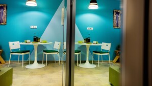 A dining area with a blue wall, white chairs, and a white table. - Emerald Suite (Athens)