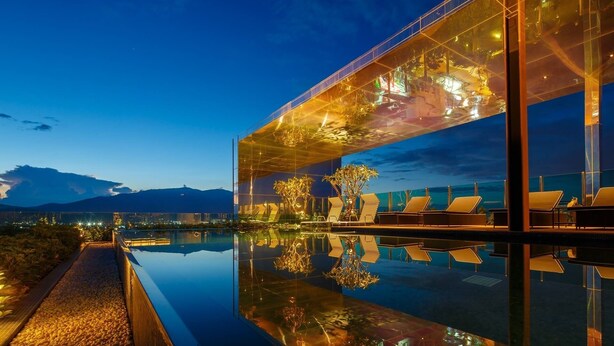 A modern building with a glass facade, outdoor seating by a reflective pool, and a view of distant mountains. - ★Luxury1BR 5mins Chiang Mai Night Bazaar Roof Pool (Chiang Mai)