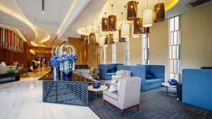 A modern lobby with a curved ceiling, blue seating areas, and a decorative floral arrangement. - ★Luxury1BR 5mins Chiang Mai Night Bazaar Roof Pool (Chiang Mai)