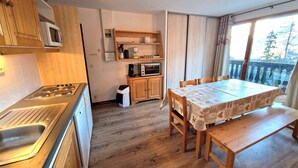 A kitchen with wooden cabinets, a stove, and a dining area with a table and chairs.