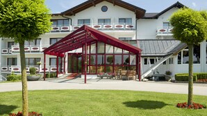 Un hotel con una zona de estar al aire libre cubierta, una escalera y un césped bien cuidado.