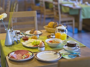 Une table de petit-déjeuner avec des assiettes remplies de nourriture, un vase de fleurs et une tasse de café.