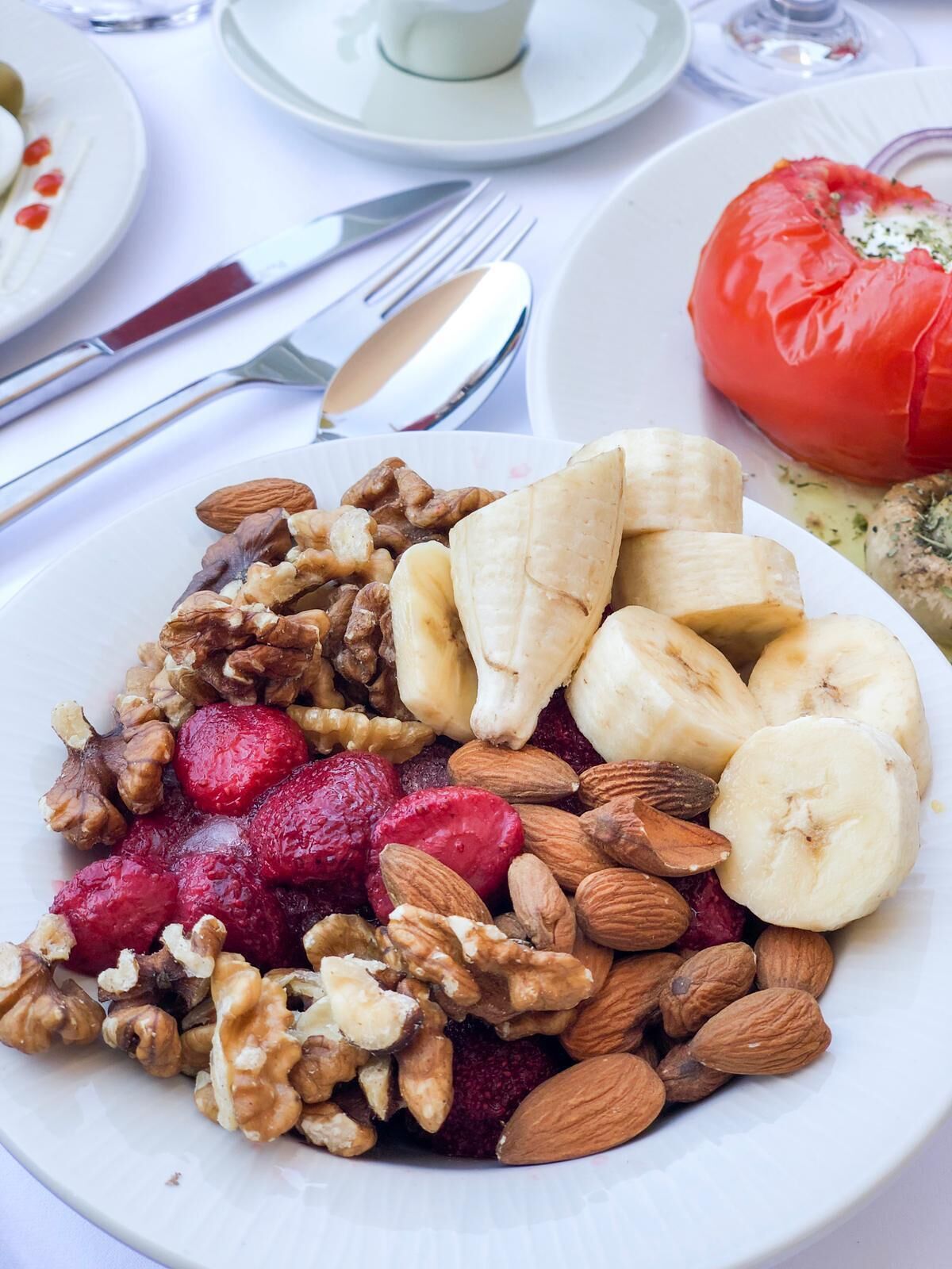 Une assiette de nourriture contenant des noix, des bananes et des baies.