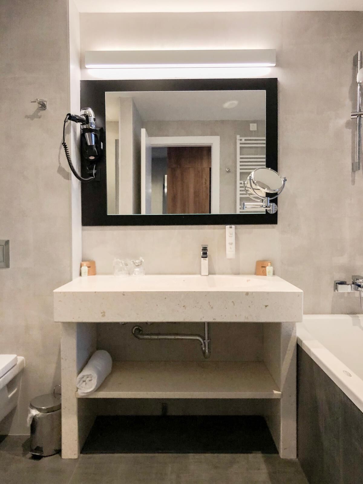 A modern bathroom with a large mirror, a white sink, and a built-in shower.
