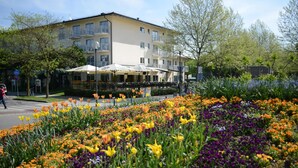A hotel with outdoor seating and a flower garden. - Hotel Dein Franz (Bad Fuessing)