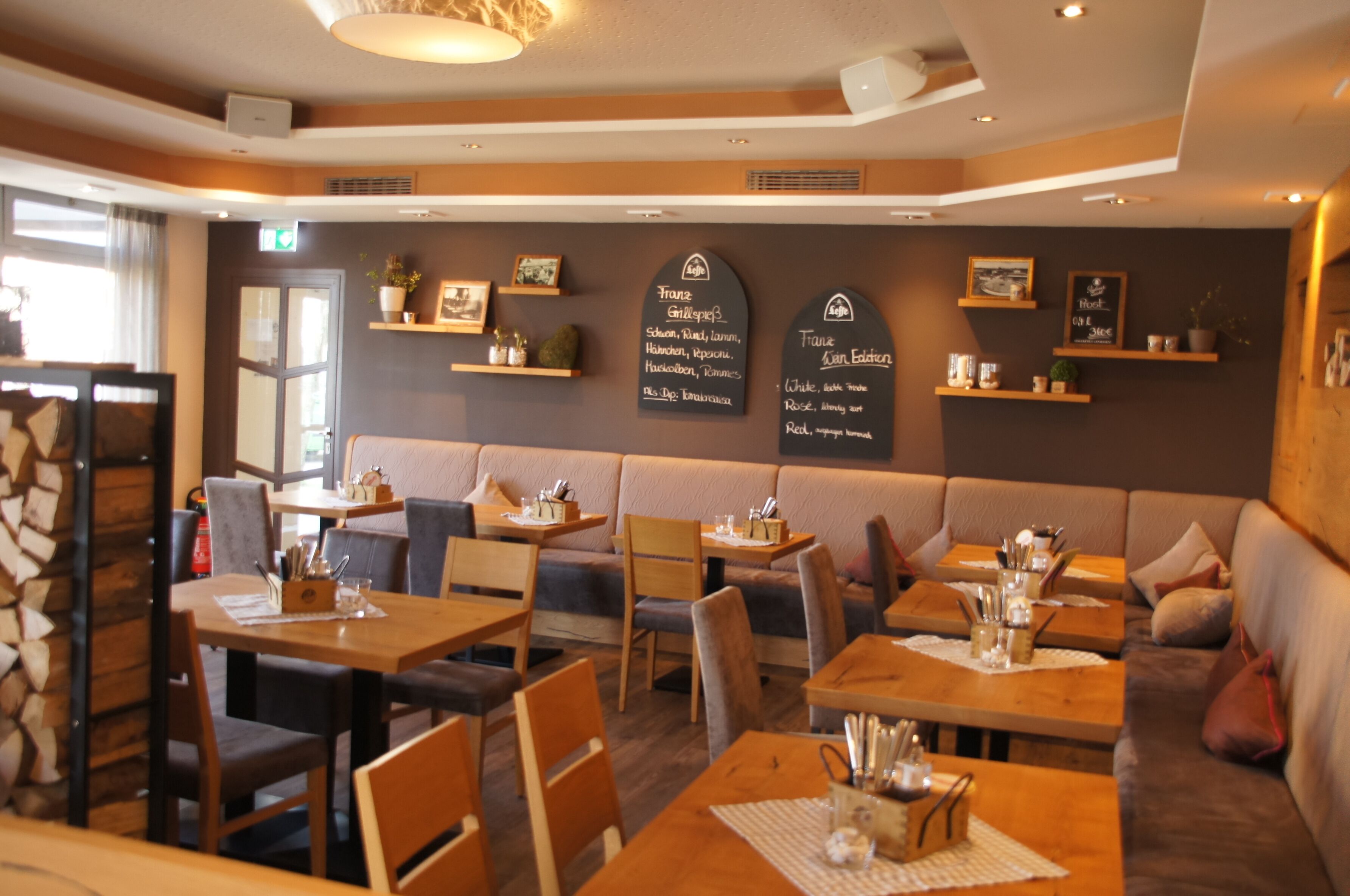 Un restaurant à l’ambiance chaleureuse, avec des tables en bois et des sièges rembourrés.
