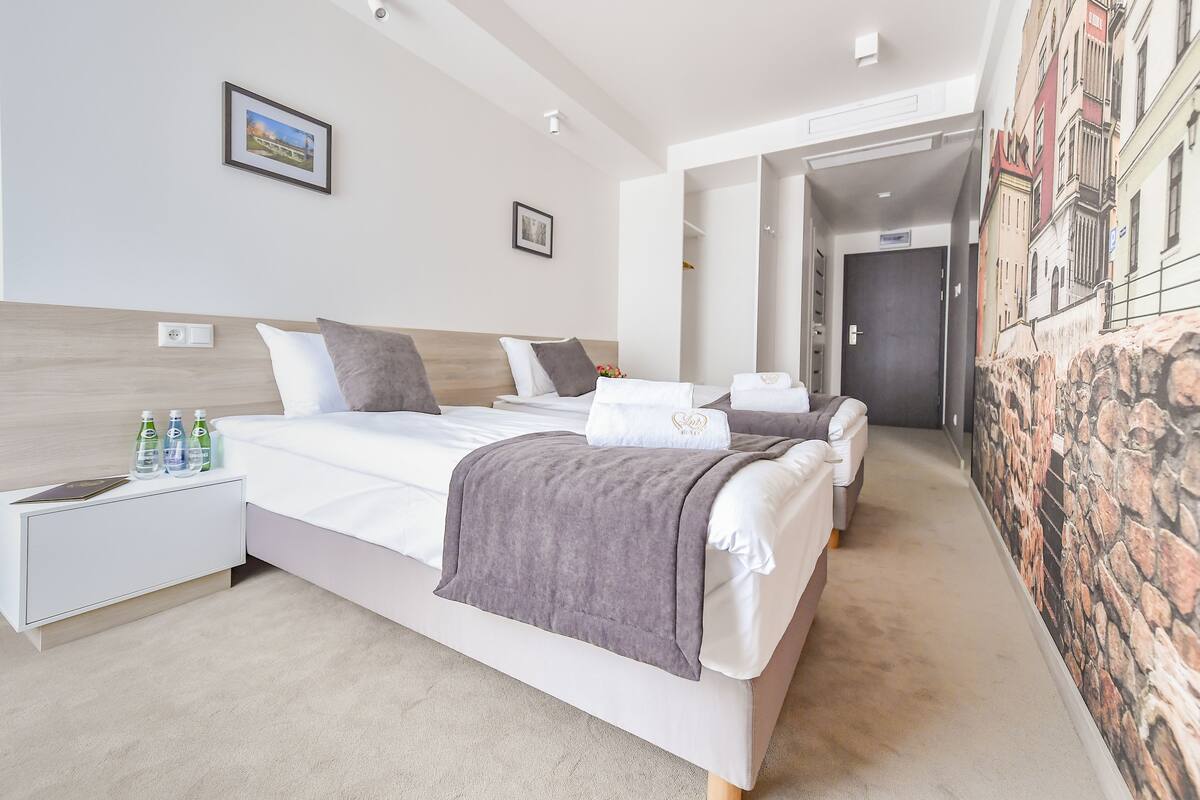 Una habitación de hotel moderna con una cama grande, mesitas de noche y un mural en la pared.