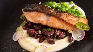 Een bord met zalm, erwten, bonen en radijsjes.