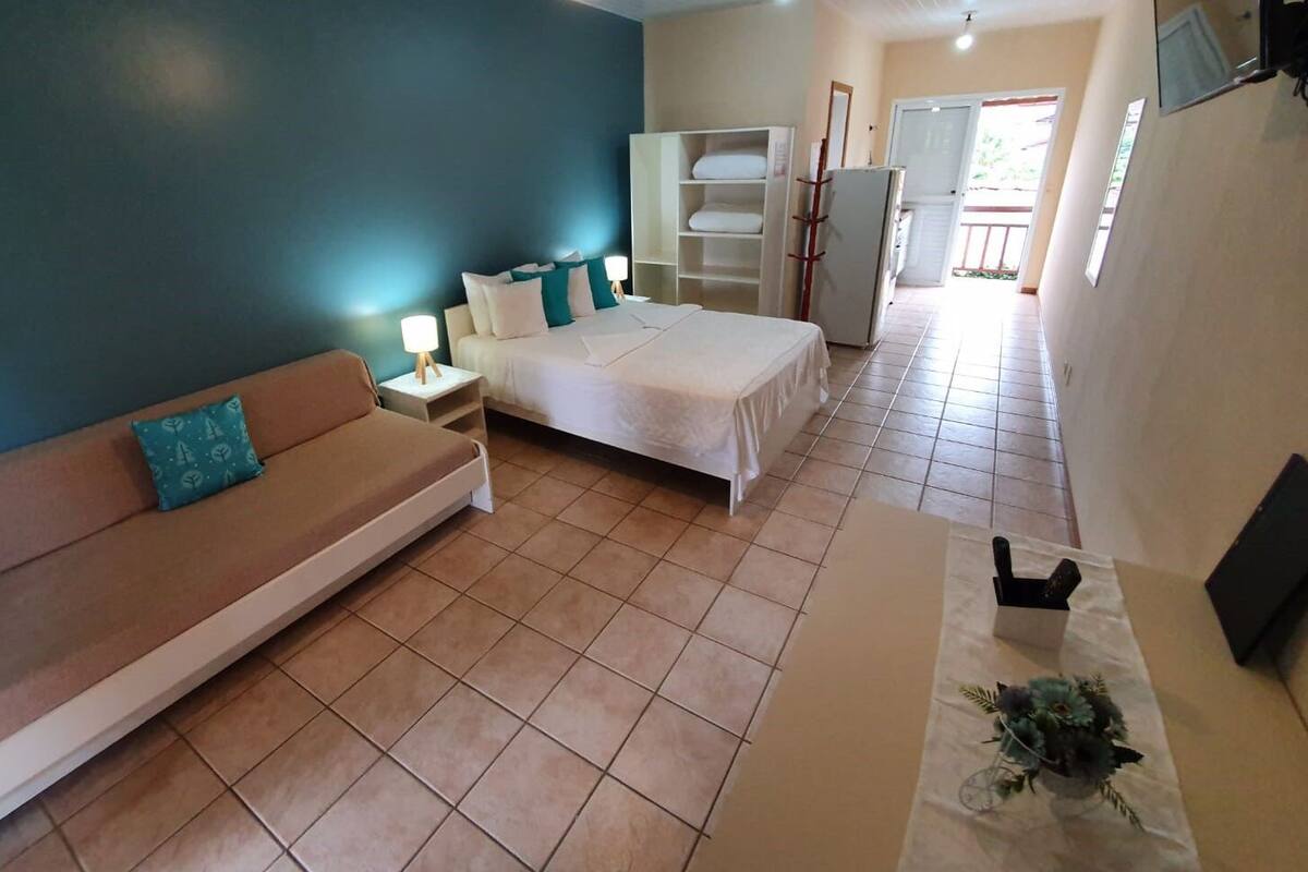 Une chambre à coucher comprenant un lit, un canapé, une armoire et une petite table avec une lampe.